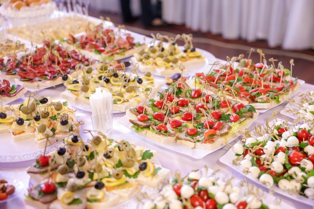 Vibrant display of assorted appetizers and finger foods at an indoor event buffet.